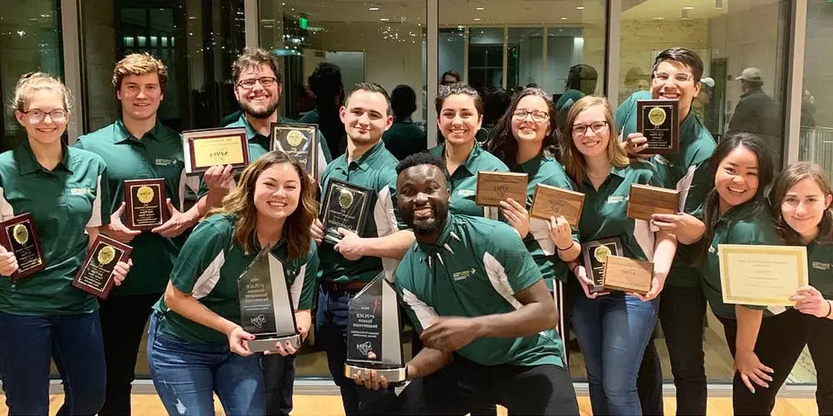 Members of the CUI Debate team hold plaques and award trophies they won at the National Parliamentary Debate Association Championship Tournament in March 2019.